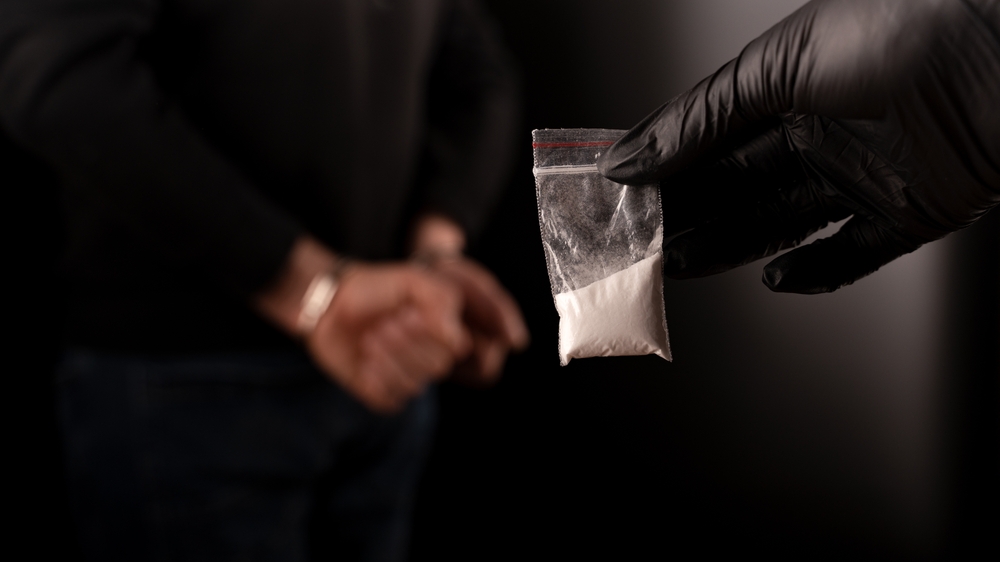 A police officer holding drugs while arresting an offender. Know what is considered a controlled substance in Texas by consulting with a Dallas criminal defense lawyer.